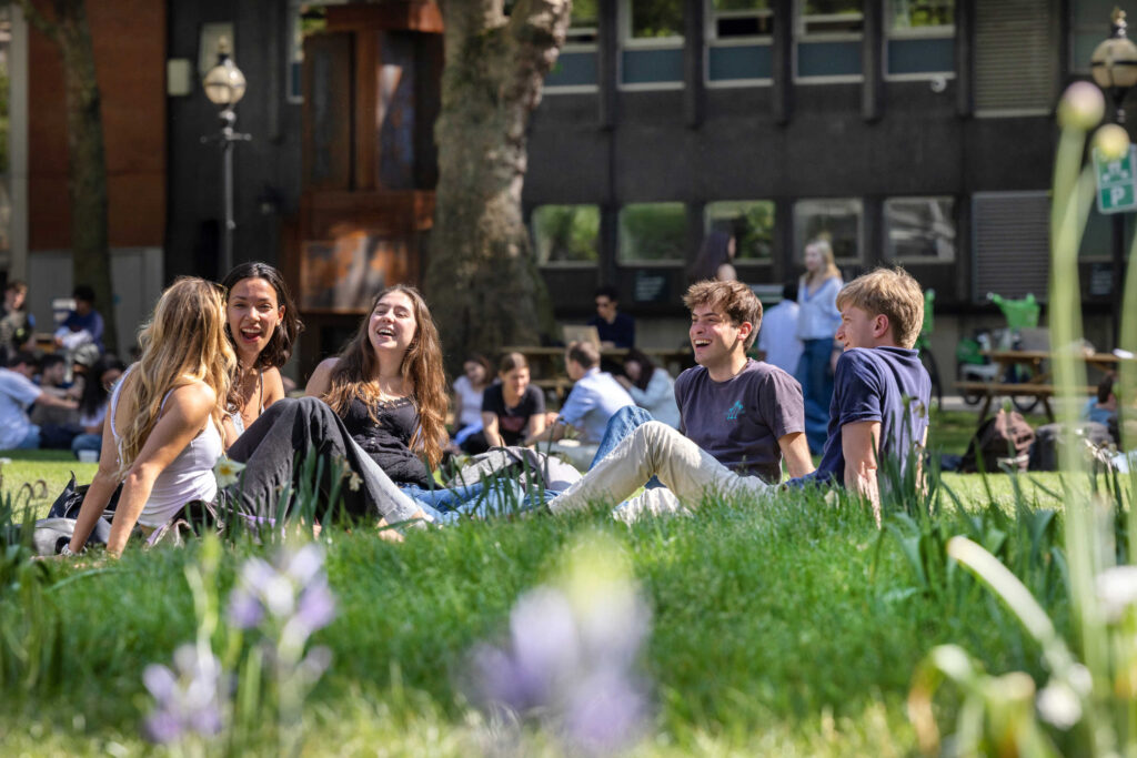 A group of students sitting on Queens Lawn at Imperial's South Kensington campus.