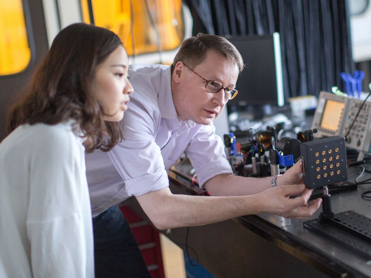 Undergraduate electrical engineering student and professor work on machinery/