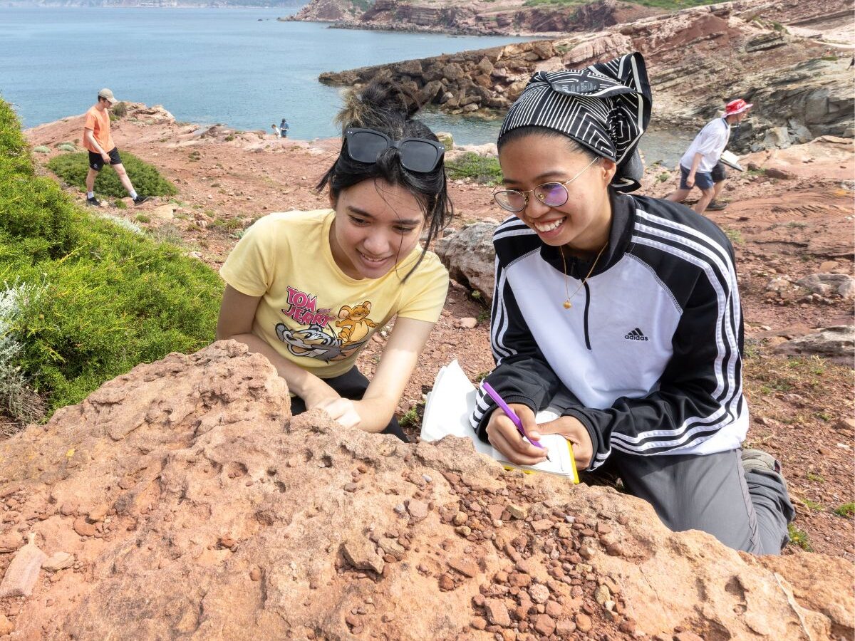 Two undergraduate Earth science and engineering students observe a rock on a Geology field trip.